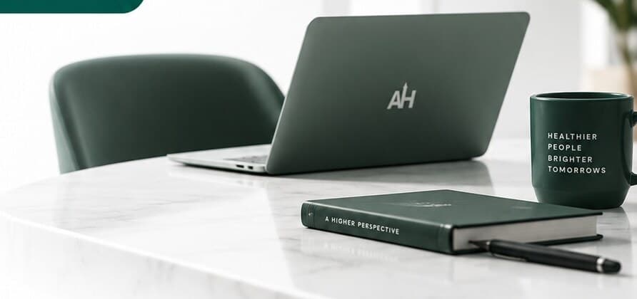 An Aura Height laptop, notebook and mug on a bright marble desk